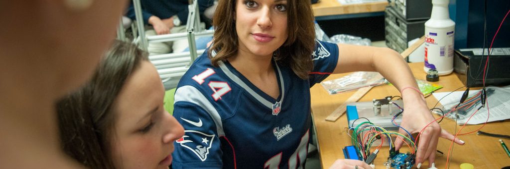 a european american female with a patriots football jersey conducting senior design research with her colleagues